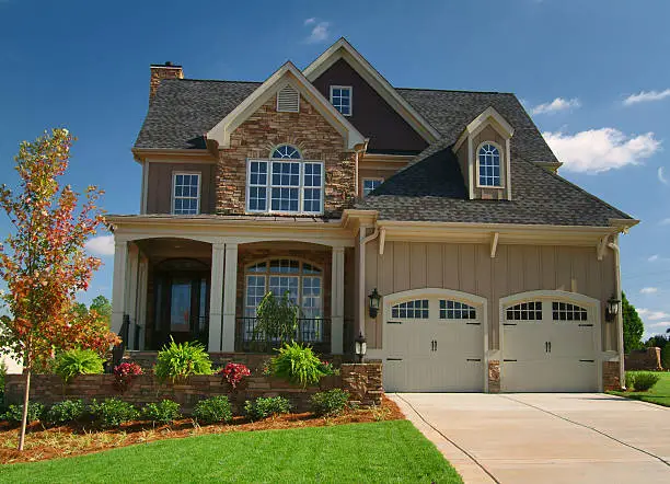 Home with warm beige exterior, white trim, and stone accents by an exterior painter in Lake County, IL.